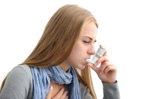 Young woman using an asthma inhaler as prevention